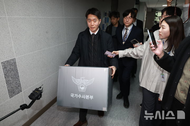 [서울=뉴시스] 고승민 기자 = 경찰이 통일교 관련 전방위적으로 압수수색에 나선 15일 서울 여의도 국회 의원회관 전재수 더불어민주당 의원실 압수수색을 마친 경찰 국가수사본부 관계자가 압수물품을 들고 건물을 나서고 있다. 2025.12.15. kkssmm99@newsis.com