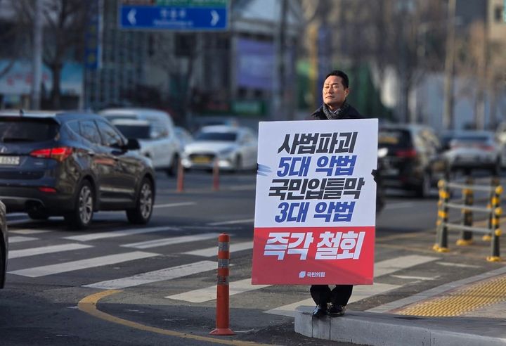 [대구=뉴시스] 국민의힘 대구시당 권오섭 대변인이 더불어민주당이 추진하고 있는 '사법파괴 5대 악법'과 '국민 입틀막 3대 악법'에 반대하는 1인 피켓시위를 하고 있다. (사진=페이스북 캡처) 2025.12.16. photo@newsis.com *재판매 및 DB 금지