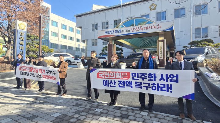 [창원=뉴시스] 강경국 기자 = 더불어민주당 경남 창원시의원단이 15일 창원시의회 정문에서 '고향의 봄' 창작 100주년 기념사업 철회를 촉구하며 피켓 및 현수막 시위를 펼치고 있다. (사진=민주당 창원시의원단 제공). 2025.12.16. photo@newsis.com *재판매 및 DB 금지