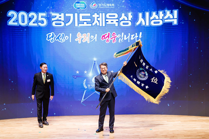 [수원=뉴시스] 16일 오후 경기도청 다산홀에서 개최된 2025 경기도체육상 시상식에서 김동연 지사가 이원성 경기도체육회장으로부터 전국체전 우승기를 봉납 받고 있다. (사진=경기도 제공) 2025.12.16. photo@newsis.com *재판매 및 DB 금지