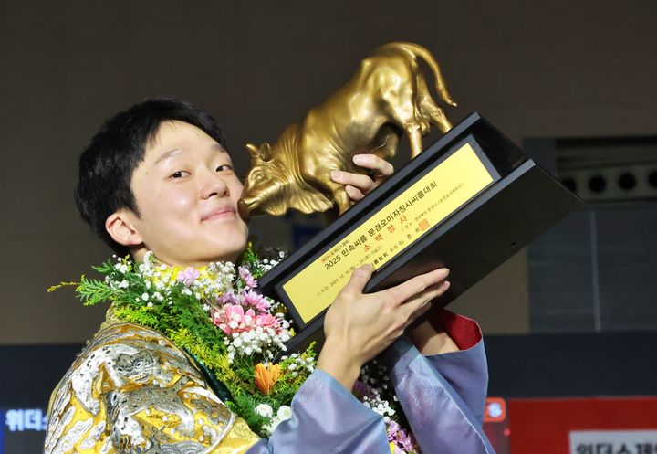 [서울=뉴시스] 16일 경상북도 문경시 문경실내체육관에서 열린 '위더스제약 2025 의성천하장사씨름대축제' 소백장사에 등극한 박상준(정읍시청)이 황소트로피를 들고 기념사진을 찍고 있다. (사진=대한씨름협회 제공) *재판매 및 DB 금지