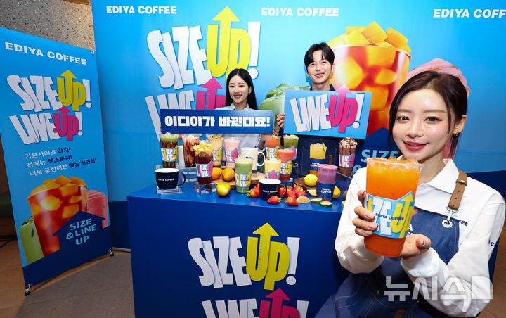 [서울=뉴시스] 최진석 기자 = 16일 서울 중구 한 이디야커피 매장에서 열린 음료 용량 확대 및 메뉴 라인업 개편을 알리는 'SIZE UP & LINE UP' 행사에서 모델이 행사를 사이즈업 잔을 들어 보이고 있다. 이디야커피는 음료 사이즈 체계를 라지와 엑스트라 기준으로 통일, 기존 14온스 중심의 운영 기준을 18온스 기반으로 정비했다. 2025.12.16. myjs@newsis.com