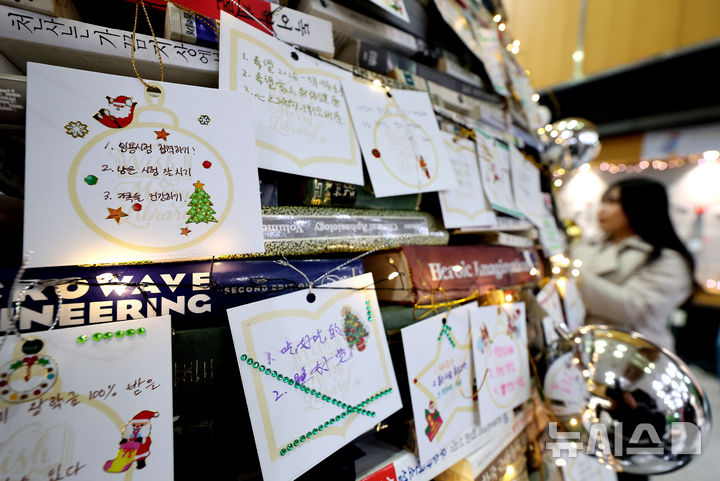 [경산=뉴시스] 이무열 기자 = 16일 경북 경산시 대구대학교 경산캠퍼스 창파도서관에서 학생들이 북(Book) 트리에 새해 소원을 담은 소원지를 매달고 있다. 대구대는 지난 2008년부터 매년 오래되거나 훼손돼 폐기 예정인 책으로 트리를 만들어 전시해 왔다. 2025.12.16. lmy@newsis.com