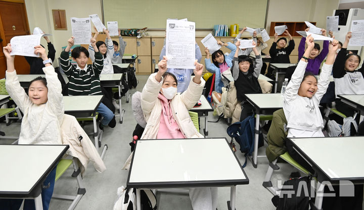 [수원=뉴시스] 김종택 기자 = 겨울방학식이 열린 16일 경기 수원시 영통구 잠원초등학교에서 4학년8반 학생들이 방학안내문을 들어보이고 있다. 2025.12.16. jtk@newsis.com