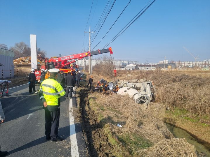 [아산=뉴시스] 17일 낮 12시께 충남 아산시 배방읍 휴대리 도로 옆 농수로에 레미콘 차량이 추락·전도돼 현장에 출동한 구급대가 구조에 나서고 있다. (사진=아산소방서 제공) 2025.12.17. photo@newsis.com *재판매 및 DB 금지