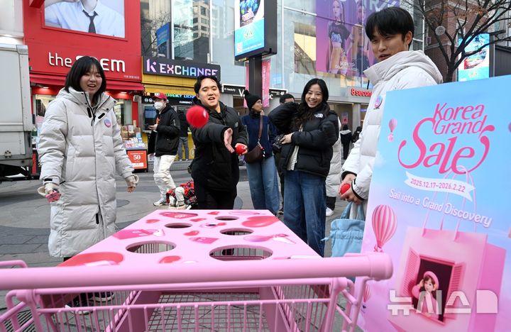 [서울=뉴시스] 권창회 기자 = 코리아그랜드세일이 시작된 17일 오전 서울 중구 명동거리 일대에서 관광객들이 홍보부스를 체험하고 있다. 문체부와 한국방문의해위원회는 외국인의 방한 관광과 소비를 촉진하기 위해 쇼핑관광축제 '2026 코리아그랜드세일'을 내년 2월 22일까지 개최한다. (공동취재) 2025.12.17. photo@newsis.com