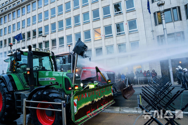 [AP/뉴시스] 18일 유럽연합 정상회의 본부건물 앞 도로를 막는 농부시위대 트랙터에 경찰이 물대포를 쏘고 있다