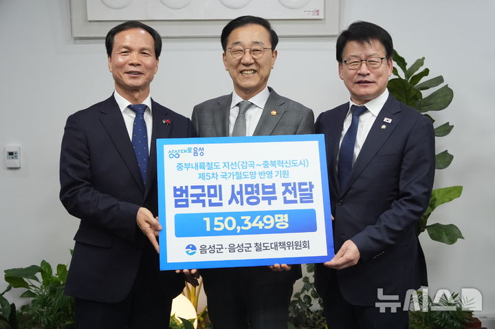 [음성=뉴시스] 조병옥(왼쪽) 충북 음성군수와 더불어민주당 임호선 의원이 18일 국회에서 김윤덕 국토교통부 장관에게 '중부내륙철도 지선 5차 국가철도망 구축계획 반영 기원' 서명부를 전달하며 기념촬영을 하고 있다. 서명부에는 15만349명의 주민 이름이 담겼다. (사진=음성군 제공) 2025.12.18. photo@newsis.com