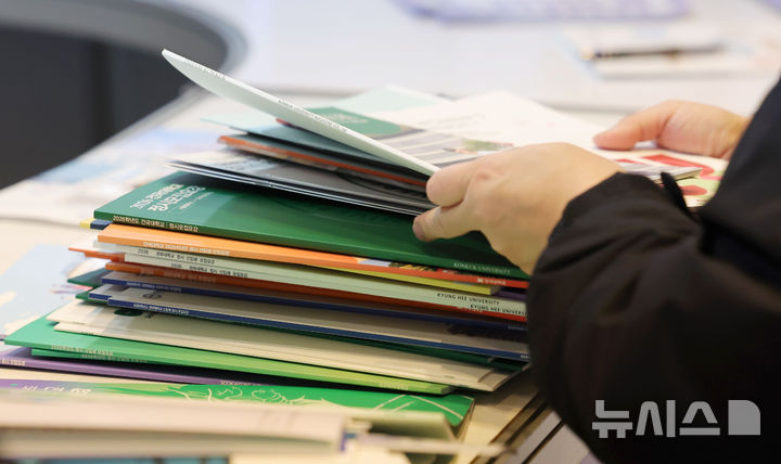 [서울=뉴시스] 홍효식 기자 = 18일 서울 강남구 코엑스에서 열린 2026학년도 정시 대학입학정보박람회를 찾은 한 학부모가 각 대학별 정시모집요강 책자를 정리하고 있다. 2025.12.18. yesphoto@newsis.com