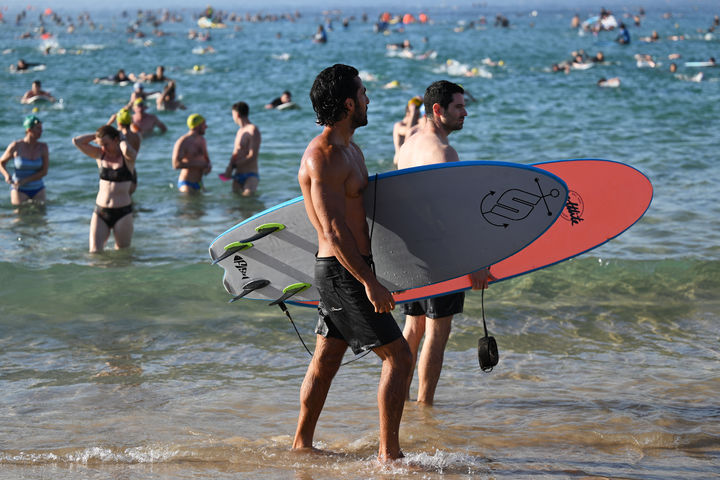 [시드니=AP/뉴시스] 19일(현지 시간) 호주 시드니 본다이비치 앞 바다에서 서퍼와 수영객들이 지난 14일 발생한 총격 희생자들을 추모하는 헌정 수영 행사를 마친 뒤 이동하고 있다. 2025.12.19.
