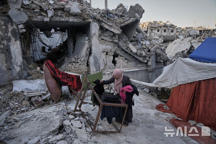 [AP/뉴시스] 11월 26일 가자 시티의 세이크 라드완 구역에서 한 여성이 무너진 옛집 위에 텐트를 치고 빨래를 널고 있다