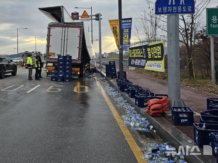 [광주=뉴시스] 19일 오전 7시40분께 광주 북구 용두동 한 도로를 달리던 25t 트레일러에서 맥주병이 담긴 상자 100여개가 쏟아져 당국이 교통 정리 중이다. (사진 = 독자 제공) 2025.12.19. photo@newsis.com