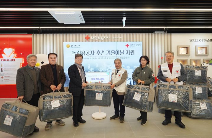 [수원=뉴시스] 광복회와 대한적십자사 경기도지사 관계자들이 독립유공자 후손에게 전달한 이불세트를 들고 기념 촬영을 하고 있다. (사진=경기적십자 제공) 2025.12.23. photo@newsis.com *재판매 및 DB 금지