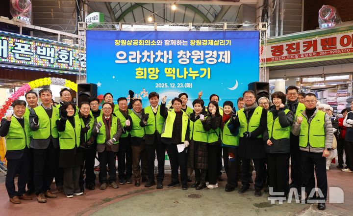 [창원=뉴시스]23일 오후 창원특례시 의창구 명서전통시장에서 열린 창원상공회의소 주최 '으라차차 창원경제! 희망 떡 나누기' 행사 참석자들이 기념촬영하고 있다.(사진=창원상공회의 제공) 2025.12.23. photo@newsis.com