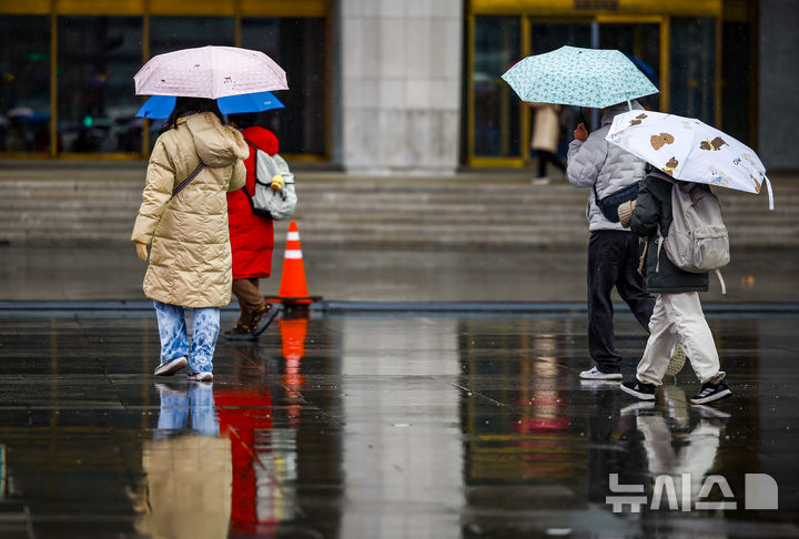 [서울=뉴시스] 정병혁 기자 = 우박과 비가 내린 23일 서울 종로구 광화문광장에서 우산을 쓴 시민들이 이동하고 있다. 2025.12.23. jhope@newsis.com