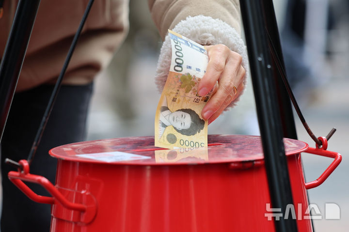 [서울=뉴시스] 권창회 기자 = 크리스마스 이브인 24일 오후 서울 중구 명동거리에 놓인 구세군 자선냄비에 한 시민이 성금을 넣고 있다. 2025.12.24. kch0523@newsis.com