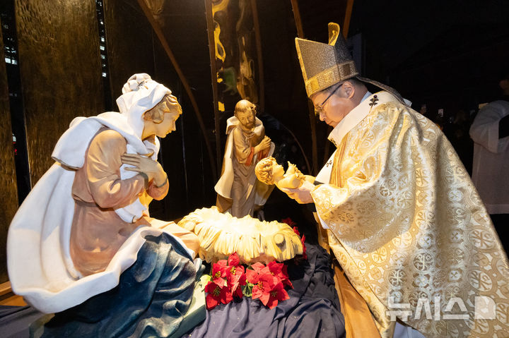 [서울=뉴시스] 황준선 기자 = 천주교 서울대교구장 정순택 대주교가 성탄절인 25일 서울 중구 명동대성당 앞마당에서 주님 성탄 대축일 밤 미사를 앞두고 아기 예수를 말 구유에 안치하는 '구유 예절' 의식을 하고 있다. 2025.12.25. hwang@newsis.com