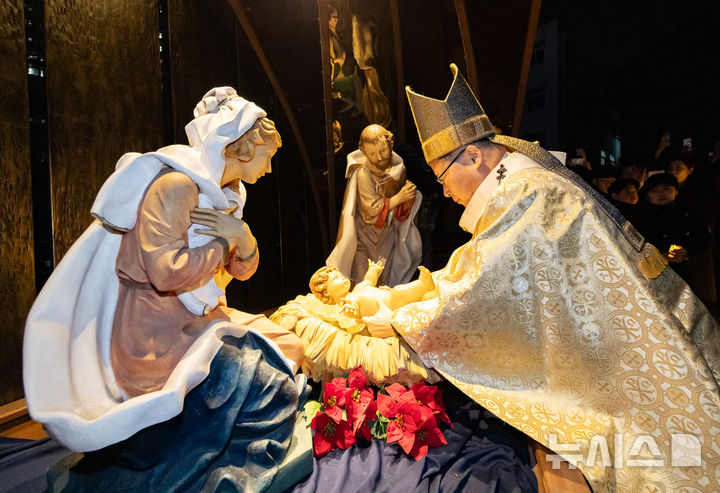 [서울=뉴시스] 황준선 기자 = 천주교 서울대교구장 정순택 대주교가 성탄절인 25일 서울 중구 명동대성당 앞마당에서 주님 성탄 대축일 밤 미사를 앞두고 아기 예수를 말 구유에 안치하는 '구유 예절' 의식을 하고 있다. 2025.12.25. hwang@newsis.com