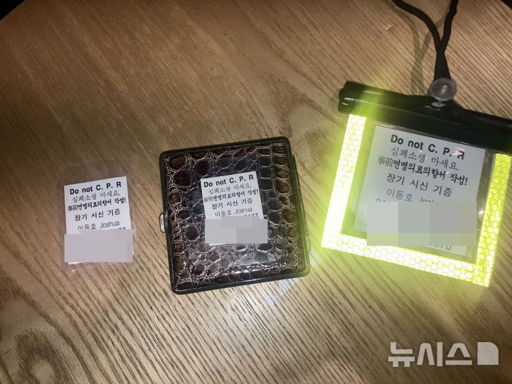 [서울=뉴시스]김경민 인턴기자=전직 공무원 이동호씨(76)가 지갑과 휴대전화에 소지하고 다니는 'Do not CPR'(심폐소생술 거부)이라는 문구가 적힌 배지와 종이. 2025.12.26 photo@newsis.com