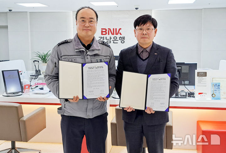 [창원=뉴시스]BNK경남은행 이수찬(오른쪽) 지점장과 마산동부경찰서 합성지구대 윤윤태 경정이 전기통신 금융사기 예방을 위한 업무협약을 체결하고 있다.(사진=BNK경남은행 제공) 2025.12.26. photo@newsis.com