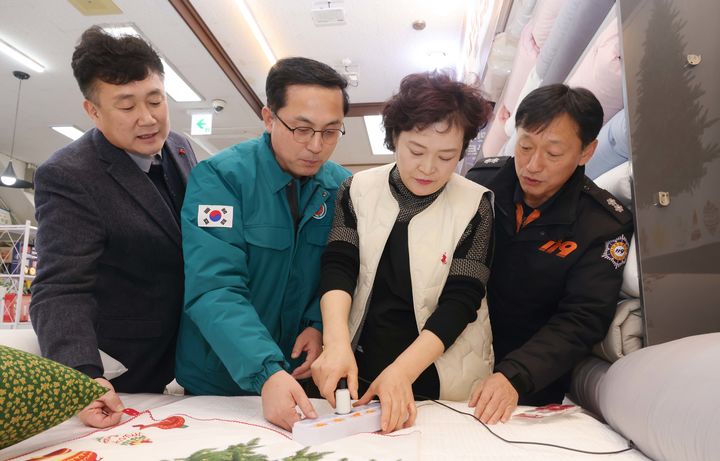 [대전=뉴시스] 조명휘 기자 = 박희조(왼쪽 두번째) 대전 동구청장이 한 전통시장 상점가 전기 콘센트에 자동소화패치를 설치하고 있다. (사진= 동구청 제공) 2025.12.26. photo@newsis.com *재판매 및 DB 금지