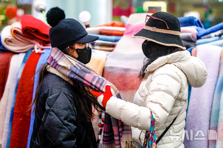 [서울=뉴시스] 정병혁 기자 = 한파주의보가 해제된 27일 서울 중구 명동을 찾은 여행객이 목도리를 고르고 있다. 2025.12.27. jhope@newsis.com