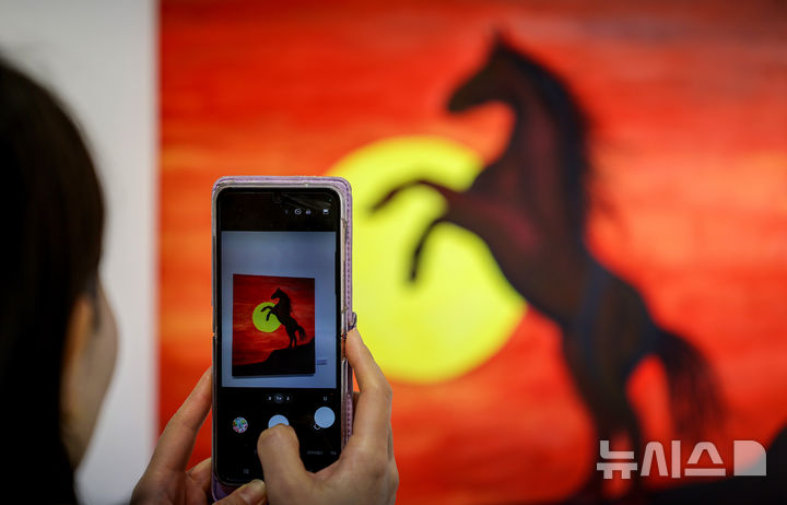 [대구=뉴시스] 이무열 기자 = 28일 대구 동구 아양아트센터 아양갤러리에서 열린 ‘2026 병오년(丙午年) 새해맞이 말(馬) 그림전’에서 관람객이 붉은 말을 주제로 한 작품을 감상하고 있다. 2025.12.28. lmy@newsis.com