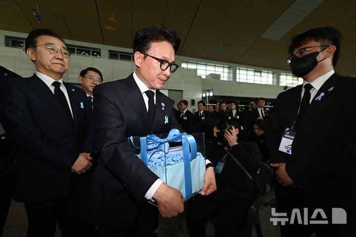 [무안=뉴시스] 이영주 기자 = 김민석 국무총리가 29일 오전 전남 무안군 무안국제공항에서 열린 12·29 제주항공 참사 추모식에 참석해 유가족들로부터 전달받은 진상규명·재발방지책 마련안이 담긴 메시지함을 들고 있다. 2025.12.29. leeyj2578@newsis.com