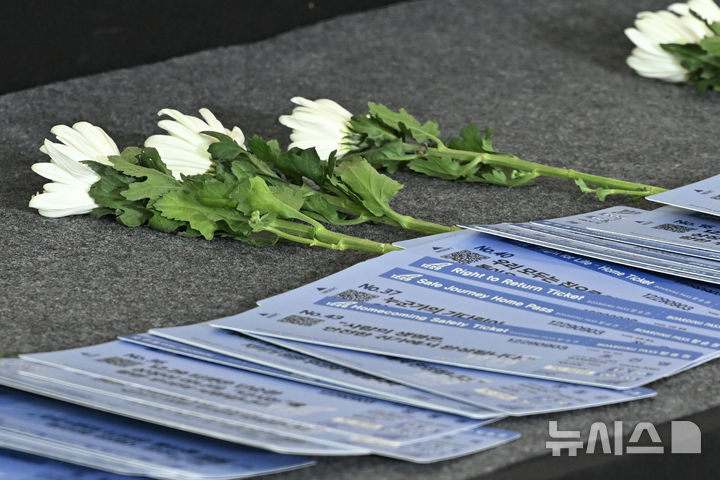 [무안=뉴시스] 이영주 기자 = 29일 오전 전남 무안국제공항에서 거행된 12·29 제주항공 참사 추모식의 제단 위로 참사 재발 방지를 염원하는 유가족들의 바람이 담긴 보딩패스 형식 메시지와 국화가 놓여있다. 2025.12.29. leeyj2578@newsis.com