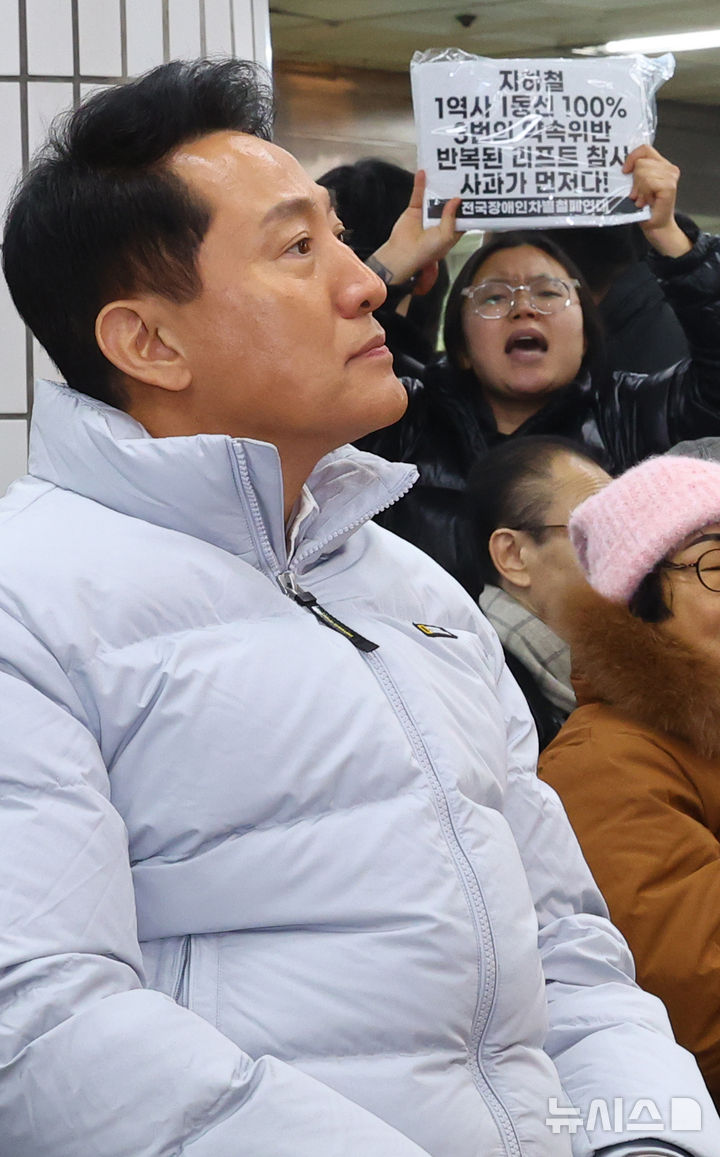 [서울=뉴시스] 박주성 기자 = 29일 오후 서울 강서구 까치산역 대합실에서 열린 전역사 1역사 1동선 확보 기념행사에서 전장연 활동가가 오세훈 서울시장에게 손피켓을 들고 리프트 참사 사과를 촉구하고 있다. 2025.12.29. park7691@newsis.com