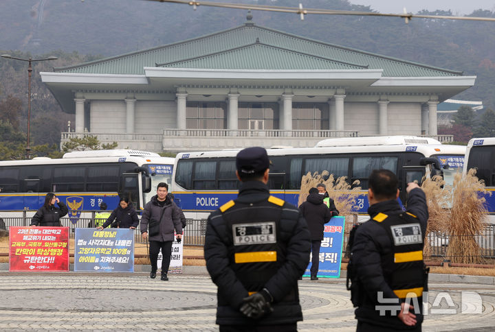 [서울=뉴시스] 홍효식 기자 = 이재명 대통령이 청와대 집무를 시작한 29일 서울 종로구 청와대 분수대 앞에서 시민사회단체들이 집회를 하고 있는 가운데 경찰들이 업무를 보고 있다. 2025.12.29. yesphoto@newsis.com