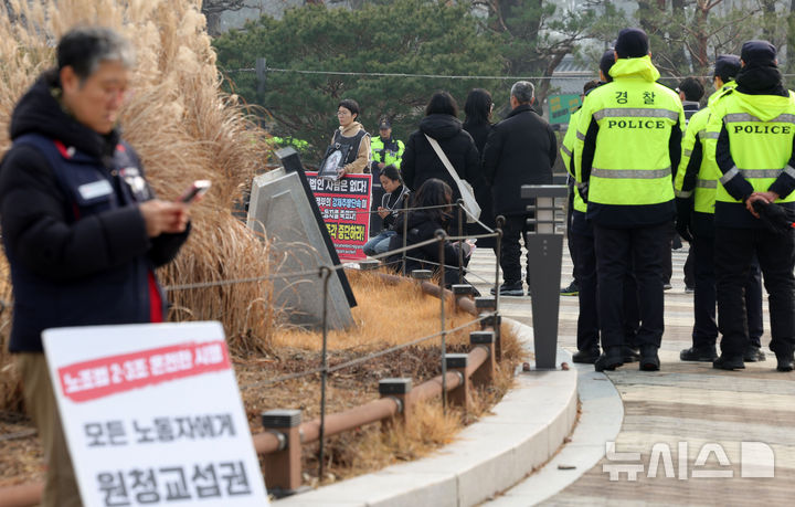 [서울=뉴시스] 홍효식 기자 = 이재명 대통령이 청와대 집무를 시작한 29일 서울 종로구 청와대 분수대 앞에서 시민사회단체들이 집회를 하고 있는 가운데 경찰들이 업무를 보고 있다. 2025.12.29. yesphoto@newsis.com