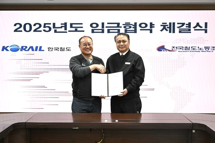 [서울=뉴시스] 정정래 코레일 사장직무대행(오른쪽)이 지난 30일 오후 서울사옥에서 강철 전국철도노동조합 위원장과 ‘2025년도 임금협약서’에 서명하며 기념촬영을 하고 있다. 2025.12.30. (사진=코레일 제공) photo@newsis.com *재판매 및 DB 금지