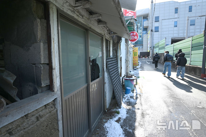[광주=뉴시스] 이현행 기자 = 지난 26일 오후 광주 광산구 광주송정역 인근에서 시민들이 깨지고 부서진 폐건물과 여인숙을 쳐다보며 걷고 있다. 2025.12.30. lhh@newsis.com