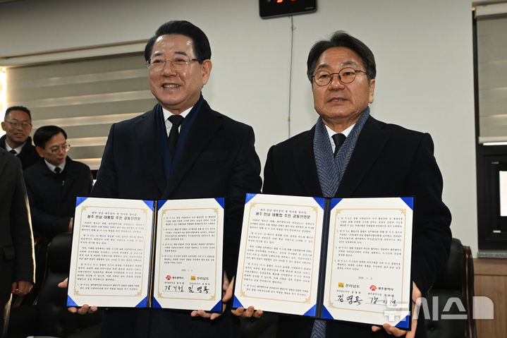 [광주=뉴시스] 이영주 기자 = 강기정(오른쪽) 광주시장과 김영록 전남도지사가 2일 오전 광주 국립5·18민주묘지에서 시도통합 선언문에 서명한 뒤 들어보이고 있다. 2026.01.02. leeyj2578@newsis.com