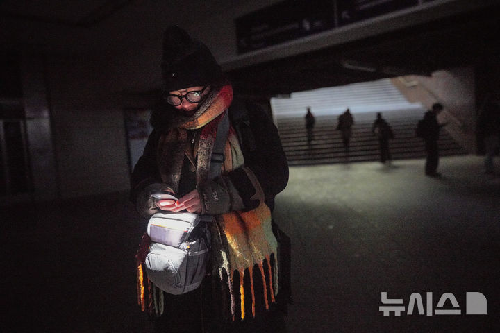 [AP/뉴시스] 3일 케이블 교량 화재로 전기가 끊긴 독일 베를린 남서부에서 한 여성이 핸드폰 손전등으로 지하철을 더듬어가고 있다 