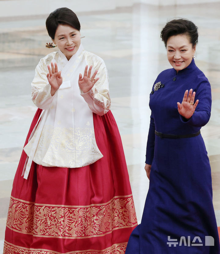 [베이징=뉴시스] 최동준 기자 = 이재명 대통령과 중국을 국빈 방문한 김혜경 여사가 펑리위안 여사와 함께 5일(현지 시간) 베이징 인민대회당에서 열린 공식환영식에서 손을 흔들며 이동하고 있다. 2026.01.05. photocdj@newsis.com