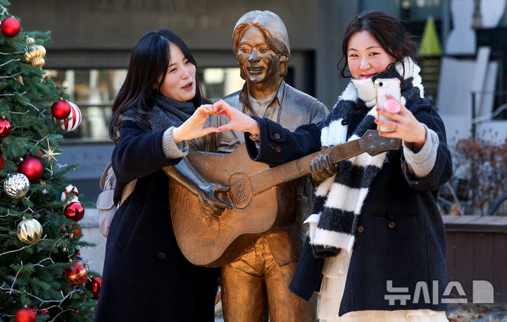 [대구=뉴시스] 이무열 기자 = 故 김광석 30주기를 맞은 6일 대구 중구 김광석 다시그리기길을 찾은 시민들이 김광석 동상에서 기념촬영을 하고 있다. 2026.01.06. lmy@newsis.com