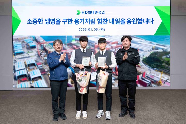 [울산=뉴시스] HD현대중공업이 지난 6일 시민의 생명을 구한 직원 자녀 등 학생 2명을 회사로 초청해 표창장과 장학금을 전달했다. 사진 왼쪽부터 HD현대중공업 금석호 사장, 문현서 군, 윤재준 군, HD현대중공업 윤형민 기사. (사진=HD현대중공업 제공) 2026.01.07. photo@newsis.com *재판매 및 DB 금지
