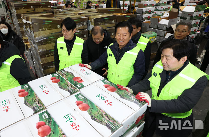 [서울=뉴시스] 조성우 기자 = 정청래(왼쪽 세 번째) 더불어민주당 대표가 7일 오전 서울 송파구 가락동 농수산물 종합도매시장 중앙청과에서 경매를 마친 사과 상자를 운반차에 싣고 있다. 2026.01.07. xconfind@newsis.com