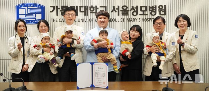 [서울=뉴시스] 서울성모병원 다섯쌍둥이 가족이 홍보대사 위촉 기념촬영을 하고 있다. 좌측부터 윤영아 신생아중환자실장(교수), 홍수빈 산부인과 교수, 정낙균 성 니콜라스 어린이병원장, 김준영·사공혜란 부부, 이지열 서울성모병원장, 박혜정 재활의학과 교수 