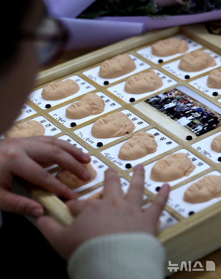 [대구=뉴시스] 이무열 기자 = 8일 대구 남구 시각장애 학생을 위한 교육기관인 대구광명학교에서 열린 2025학년도 졸업식에서 졸업생들이 3D 프린터로 제작된 졸업앨범 속 친구 얼굴을 손끝으로 만져보고 있다. 2026.01.08. lmy@newsis.com