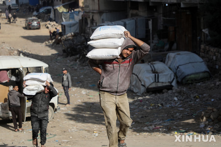 [가자시티=신화/뉴시스] 8일(현지 시간) 가자지구 가자시티에 있는 세계식량계획(WFP) 배급소에서 팔레스타인 주민들이 식량을 배급받아 돌아가고 있다. 2026.01.09.