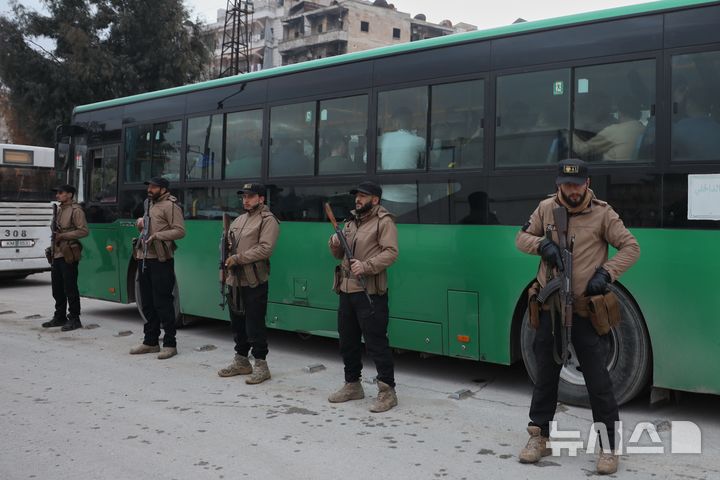 [AP/뉴시스] 시리아 북서부 대도시 알레포에서 시리아 정부군과 쿠르드족 무장조직 SDF 간 충돌이 있는 뒤 10일 정부군이 항복한 SDF 요원들을 북동부로 철수시킬 버스에 태운 뒤 경계를 서고 있다 