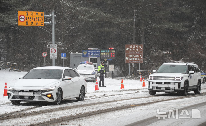 [제주=뉴시스] 우장호 기자 = 제주 산지·중산간·동부·남부에 대설특보가 내려진 11일 오전 제주시 어승생 삼거리 입구에서 제주서부경찰서 소속 경찰관이 도로통제를 하고 있다. 기상청에 따르면 제주도는 12일까지 한라산 등 고지대를 중심으로 최대 15㎝의 눈이 내려 쌓일 것으로 예측됐다. 2026.01.11. woo1223@newsis.com