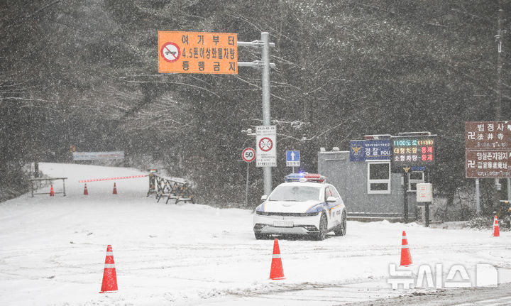 [제주=뉴시스] 우장호 기자 = 제주 산지·중산간·동부·남부에 대설특보가 내려진 11일 오전 제주시 어승생 삼거리 입구에서 제주서부경찰서 소속 경찰관이 도로통제를 하고 있다. 2026.01.11. woo1223@newsis.com