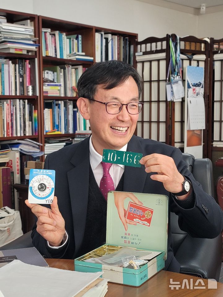 [서울=뉴시스]최희정 기자= 장상훈 국립민속박물관장이 7일 오후 서울 종로구 국립민속박물관에서 진행된 라운드 인터뷰에서 육군 논산훈련소 훈련병 시절 달았던 명찰, 시차 대조표 등 본인이 소장한 물품을 들어보이며 활짝 웃고 있다. 2026.01.12. dazzling@newsis.com