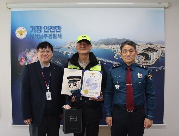 [부산=뉴시스] 13일 부산 남구청 소속 환경관리원 황은철(가운데)씨가 경찰로부터 감사장을 수여받고 있다. (사진=부산 남구 제공) 2026.01.13. photo@newsis.com *재판매 및 DB 금지