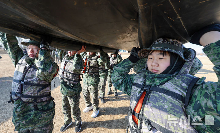 [포항=뉴시스] 이무열 기자 = 13일 경북 포항시 해병대 1사단 연병장에서 열린 ‘2026 겨울 해병대 캠프'에서 참가자들이 소형 고무보트(IBS)를 머리에 이고 이동하고 있다. 2026.01.13. lmy@newsis.com