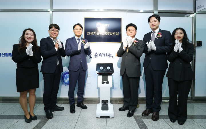 임광현 국세청장(왼쪽에서 세번째)이 19일 세종시 나성동 SM타워에서 열린 AI혁신담당관실 현판식에서 양철호 정보화담당관(왼쪽에서 두번째), 이성진 차장(오른쪽에서 세번째), 전승한 AI혁신담당관(오른쪽에서 두번째)과, K-AI 로봇(가운데)과 기념촬영을 하고 있다.(사진 : 국세청 제공) 2026.1.19. *재판매 및 DB 금지